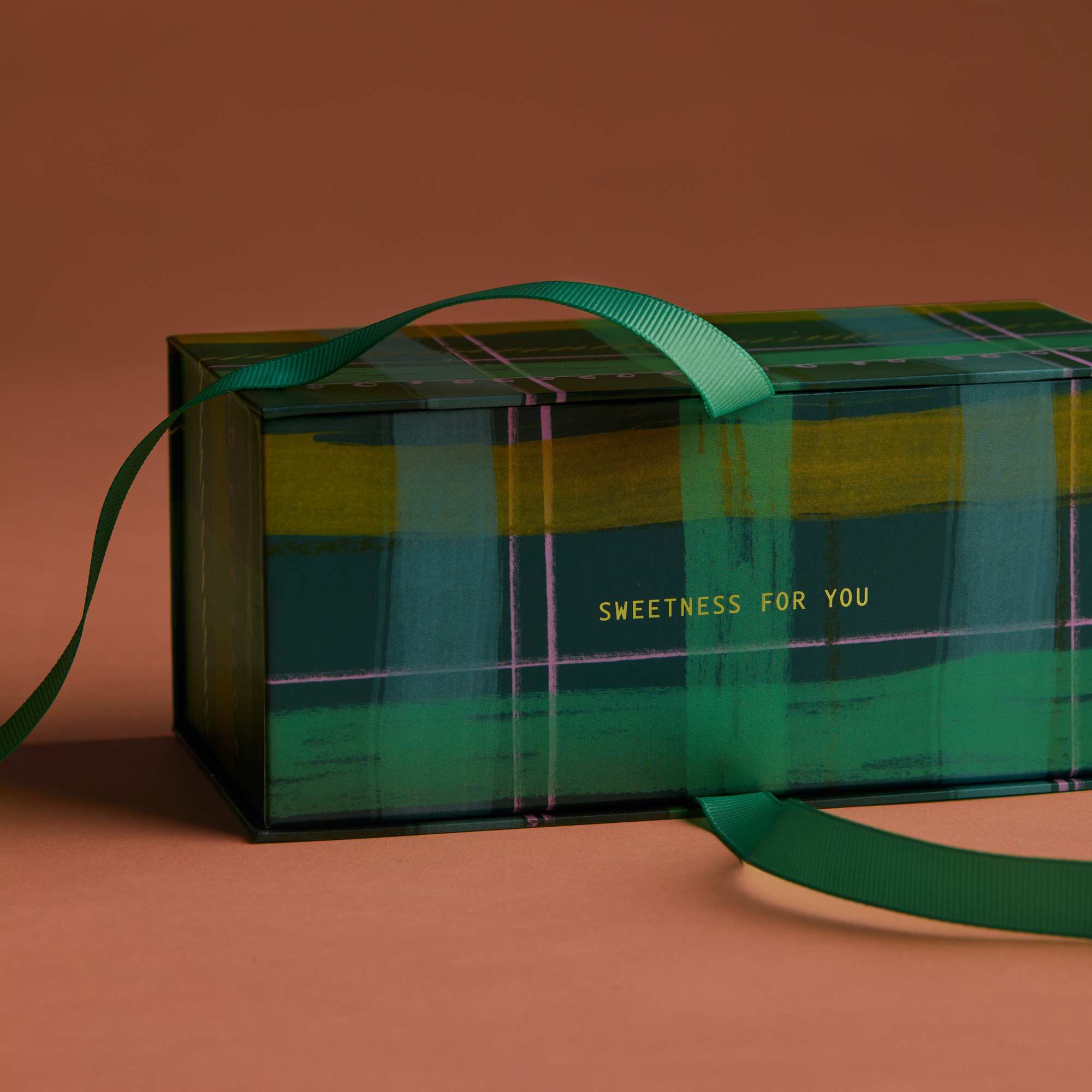 Gift box with green ribbon on a brown background