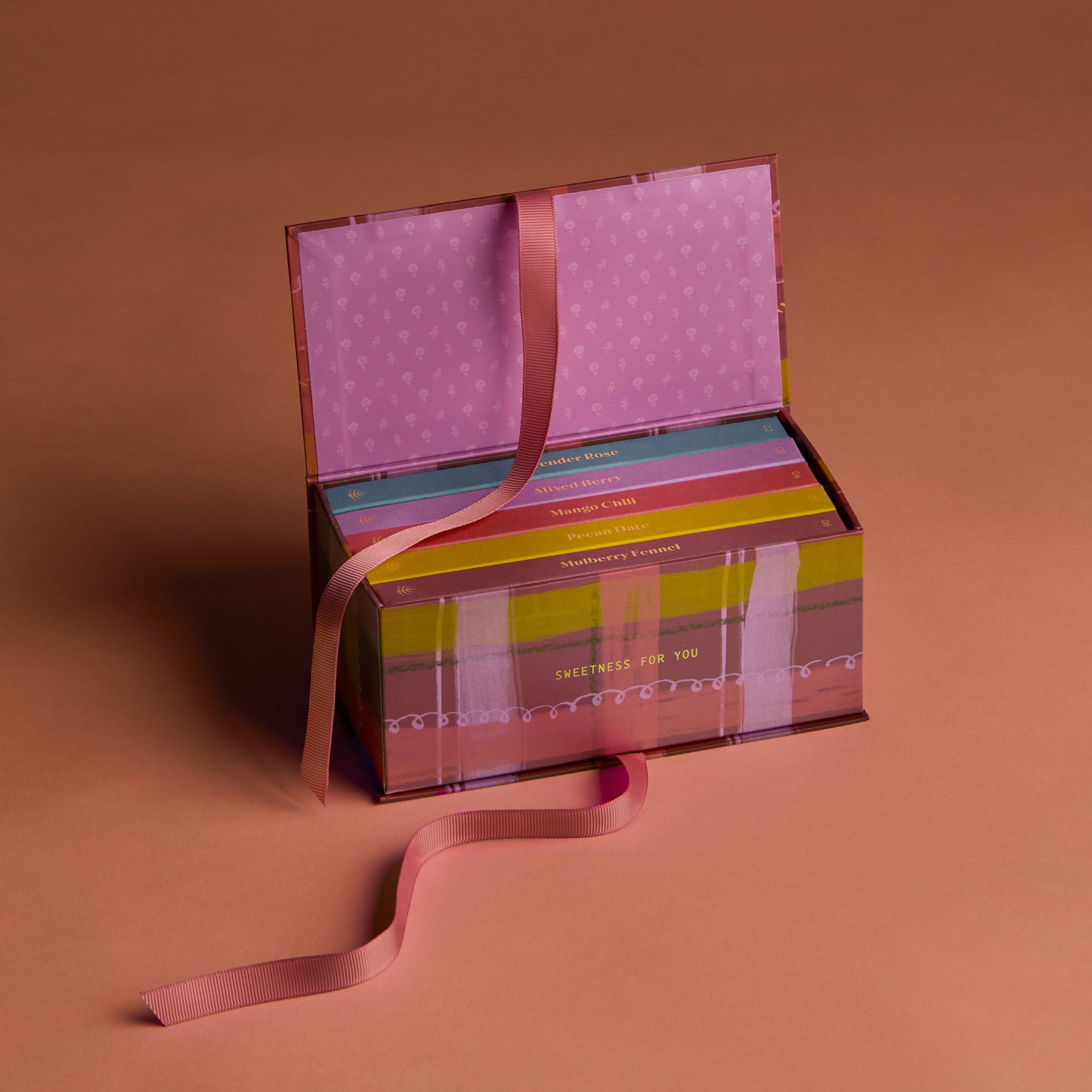 Open gift box with colorful design and pink ribbon on a brown background