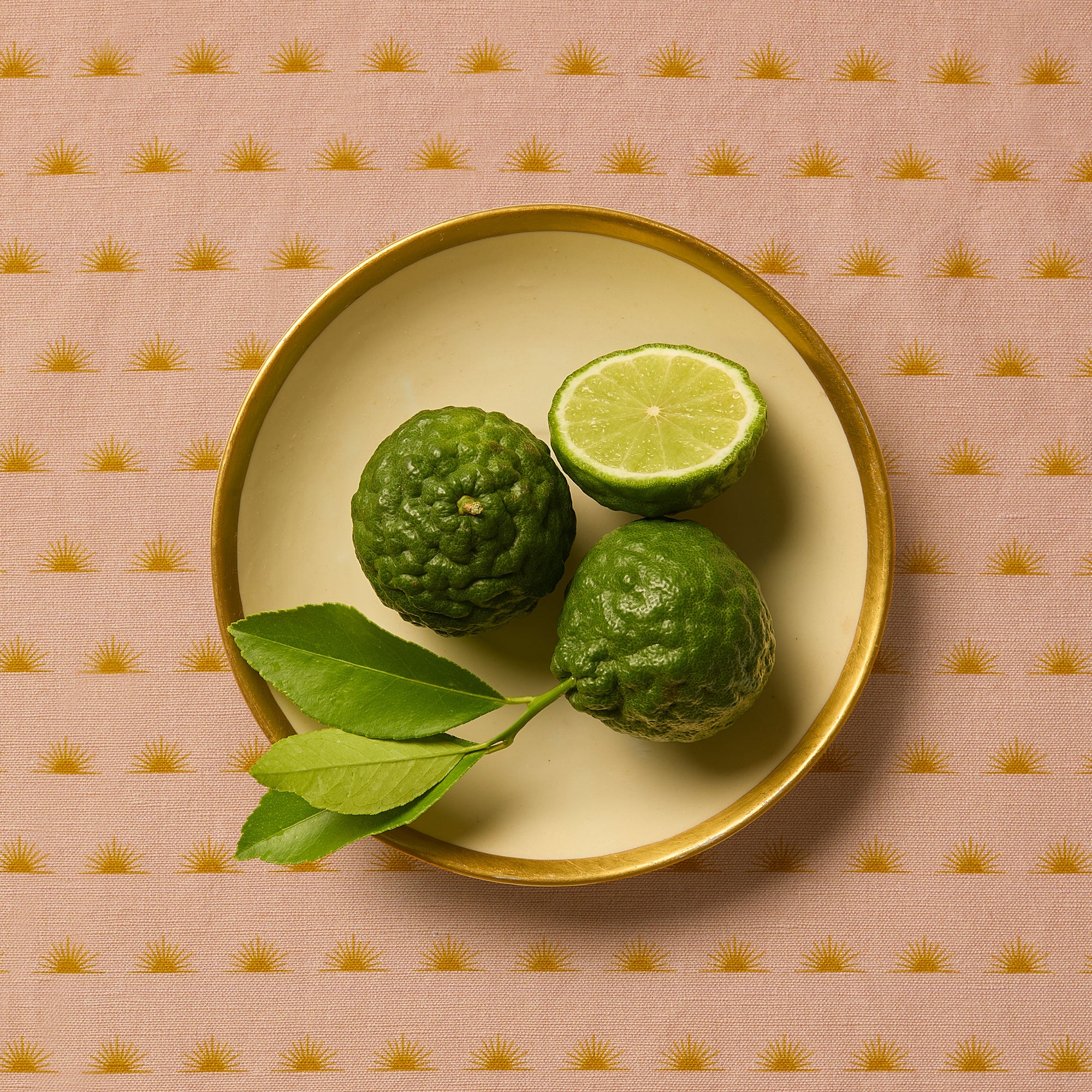 Bergamots sitting on a cream and gold plate on a patterned tablecloth