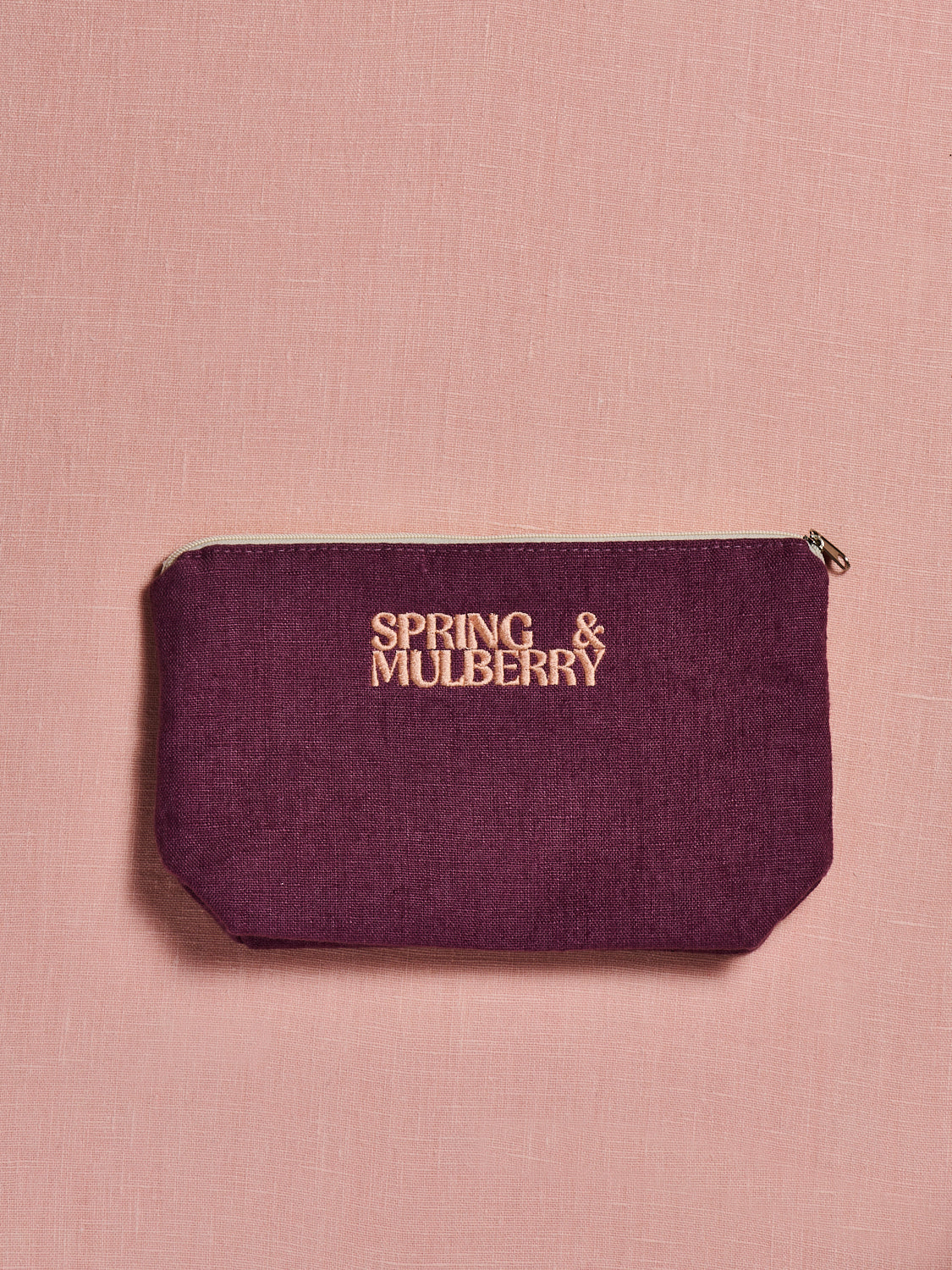 Mulberry pouch with 'Spring & Mulberry' logo on a pink background