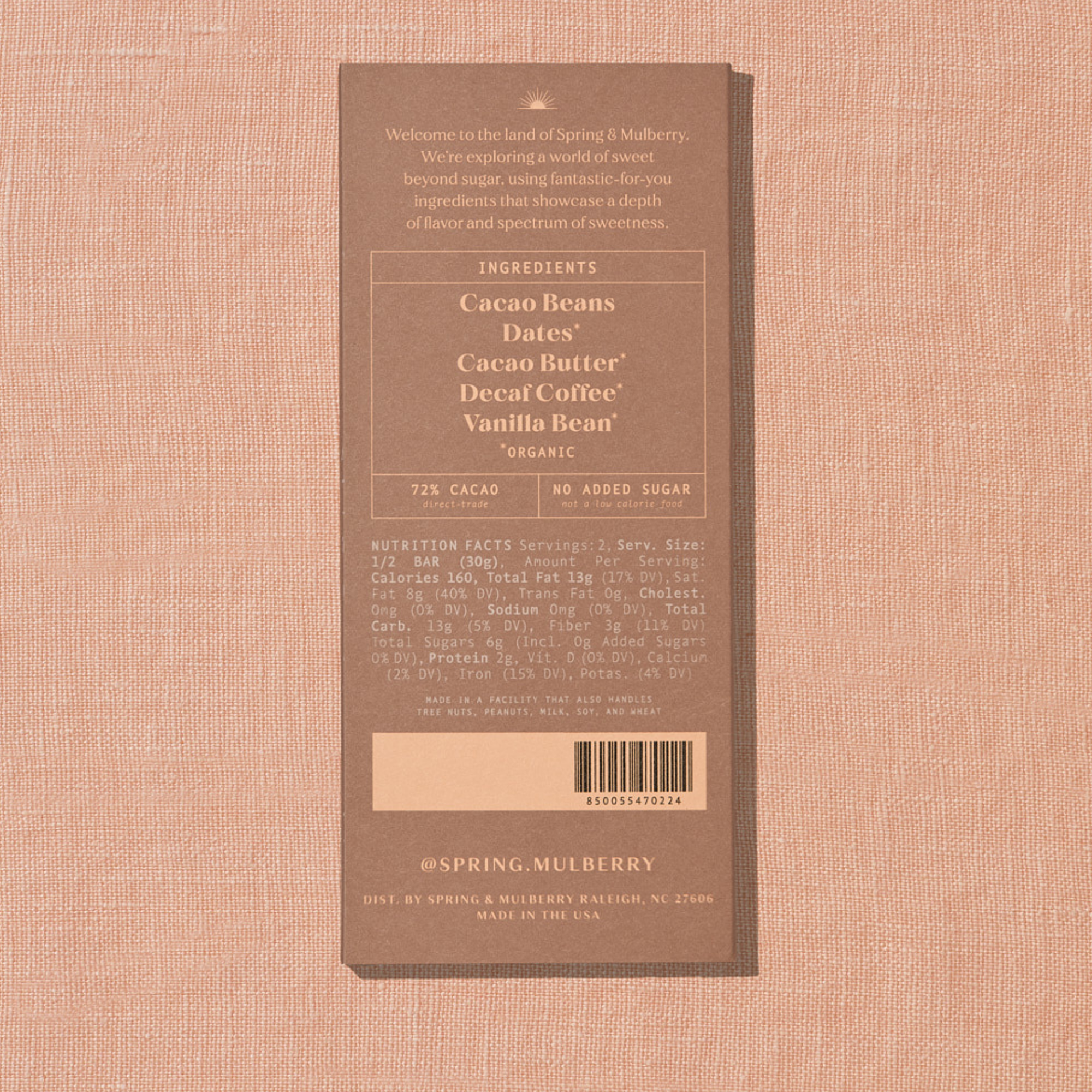 A light brown Spring & Mulberry box with its back lable showing chocolate information is laid on a warm brown background. 