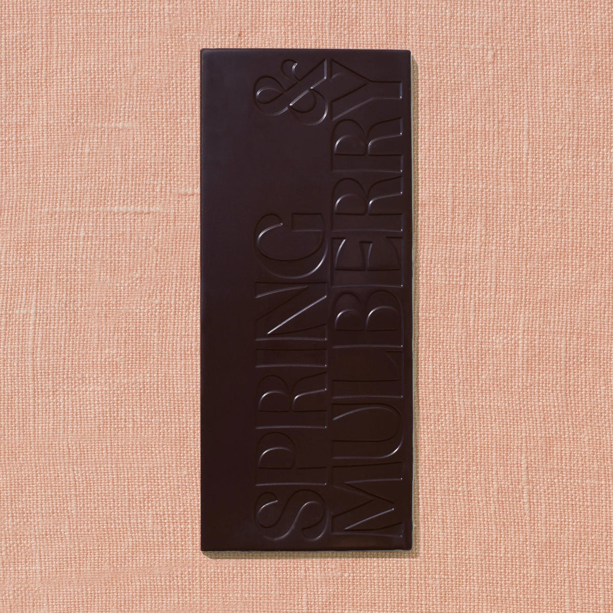 Spring & Mulberry Coffee bar featuring the brand’s embossed logo, on a soft peach textured background.