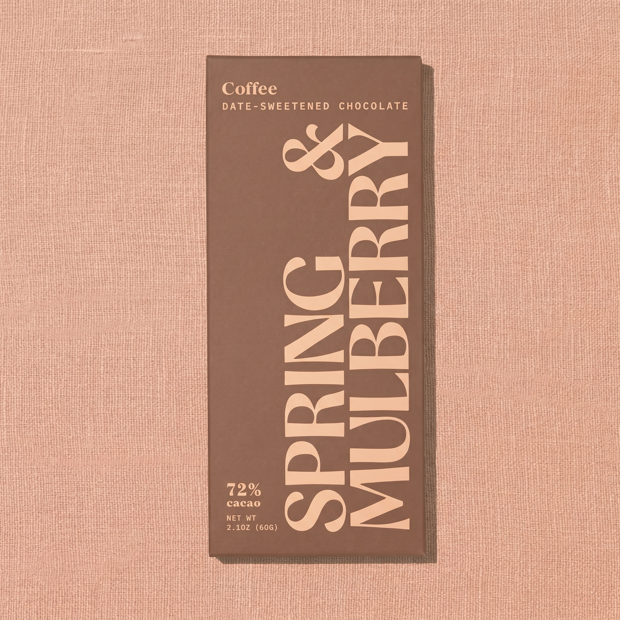 A brown Spring & Mulberry box labled Coffee date-sweetened chocolate is laid on a warm brown background. 