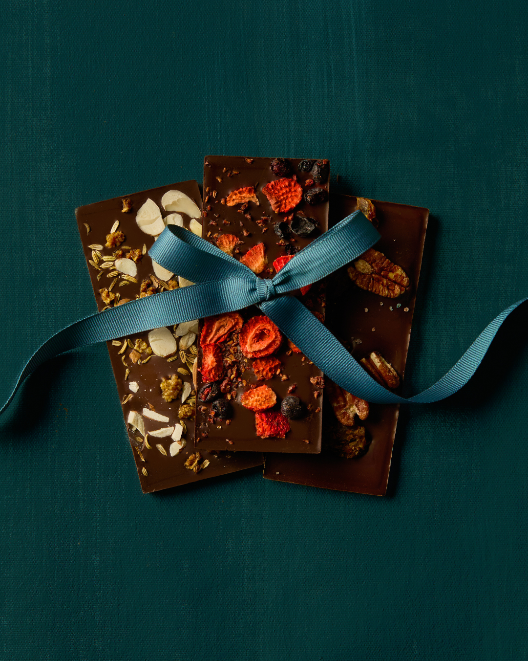 Three embellished bars tied with a ribbon on a dark green background
