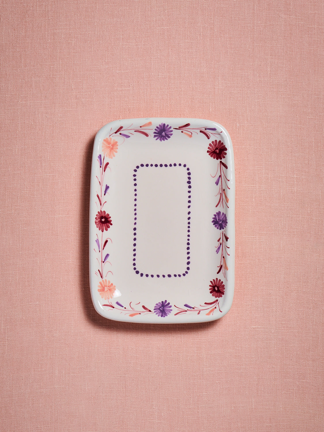 hand painted plate with peach, lavender and mulberry flowers against a pink background