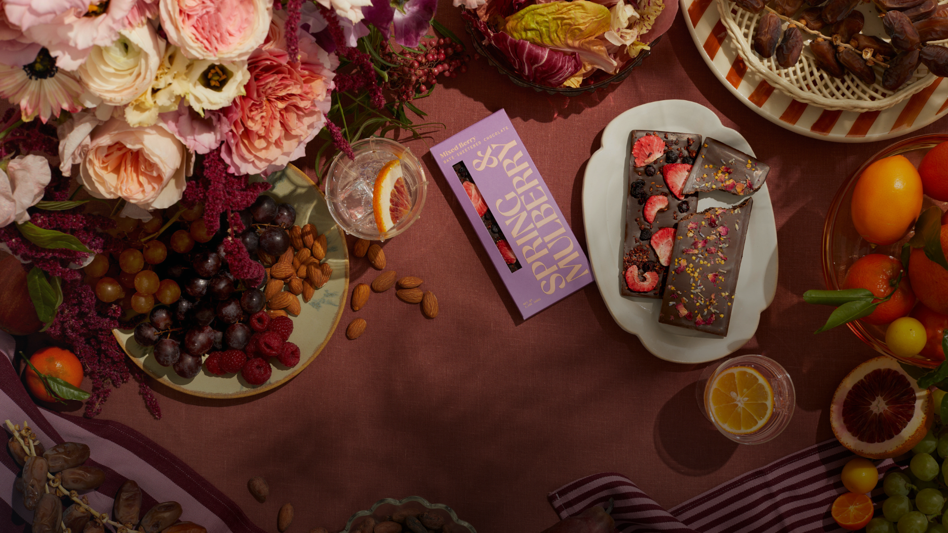 Table setting with chocolate bars, flowers, and drinks on a dark surface