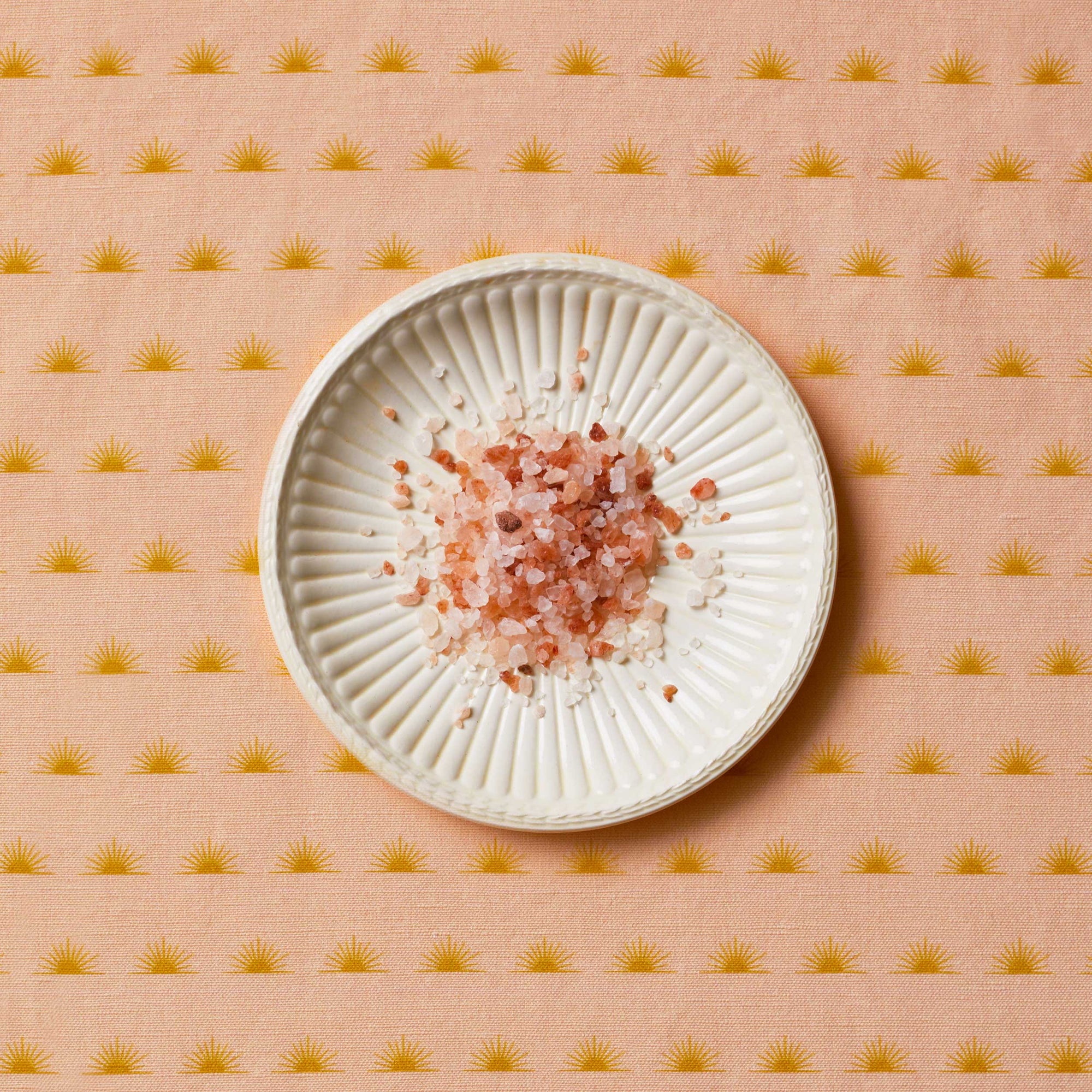 Himalayan salt sitting on a white plate on top of a patterned tablecloth