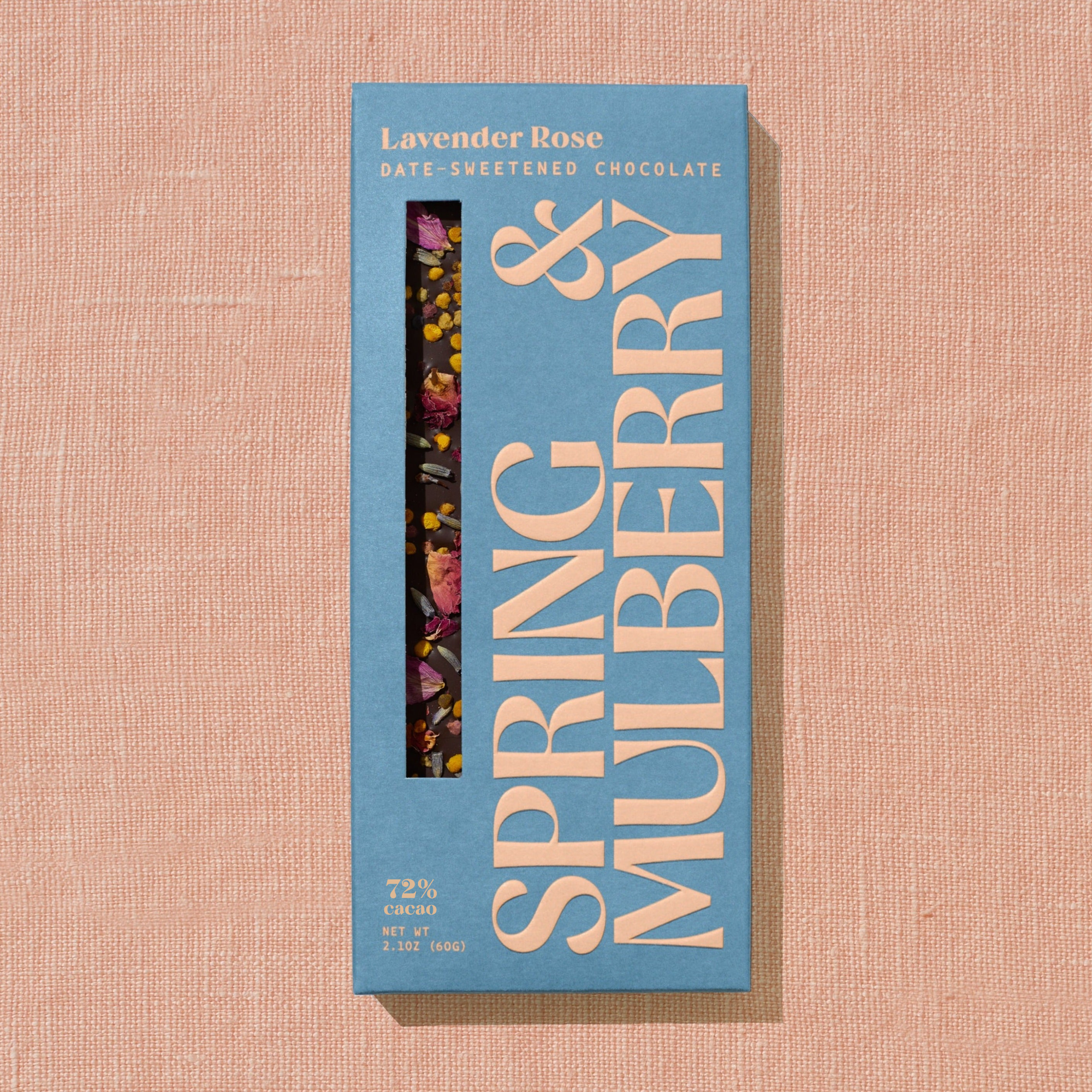 A light blue Spring & Mulberry box labled Lavender Rose date-sweetened chocolate is laid on a warm brown background. 