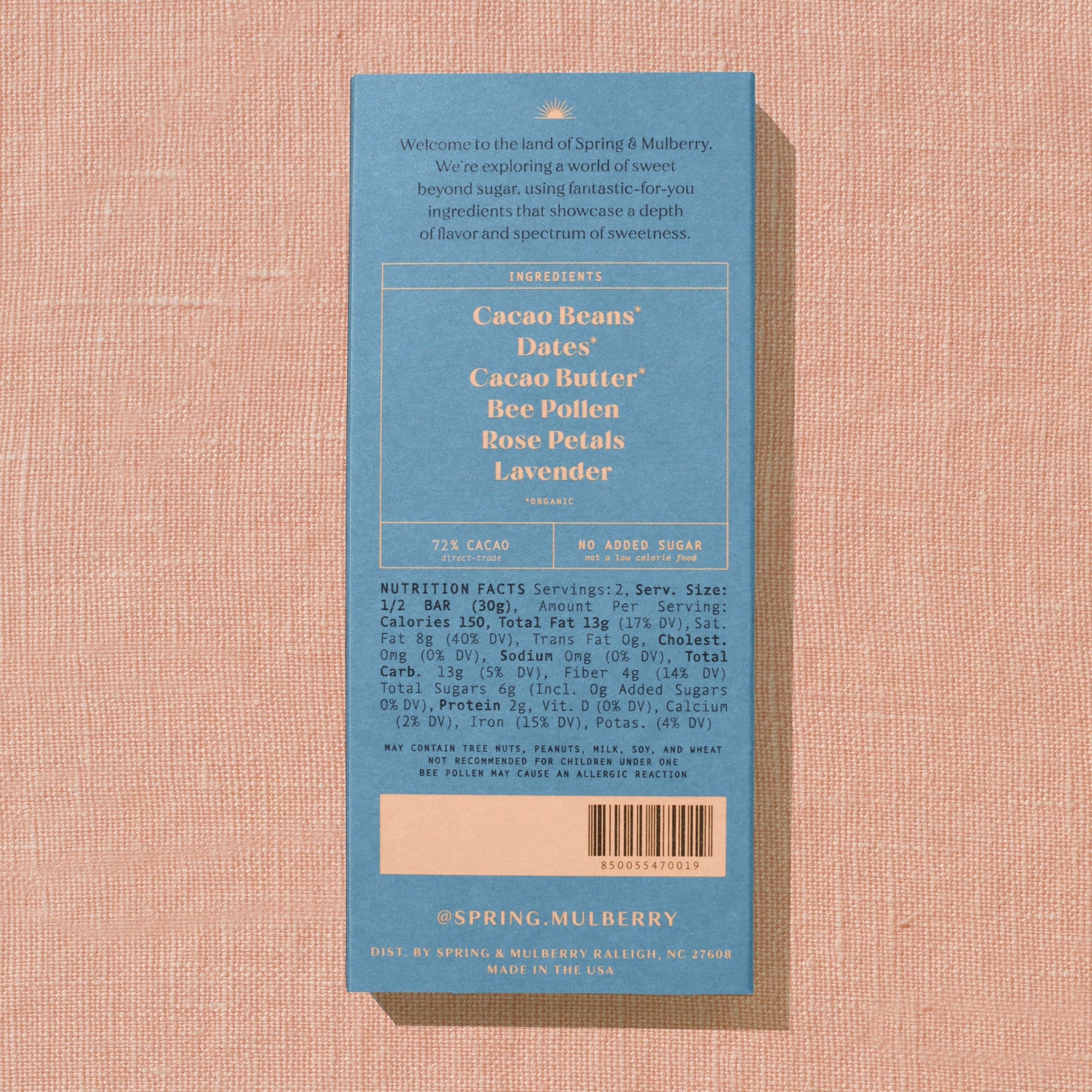 A light blue Spring & Mulberry box with its back lable showing chocolate  information is laid on a warm brown background. 
