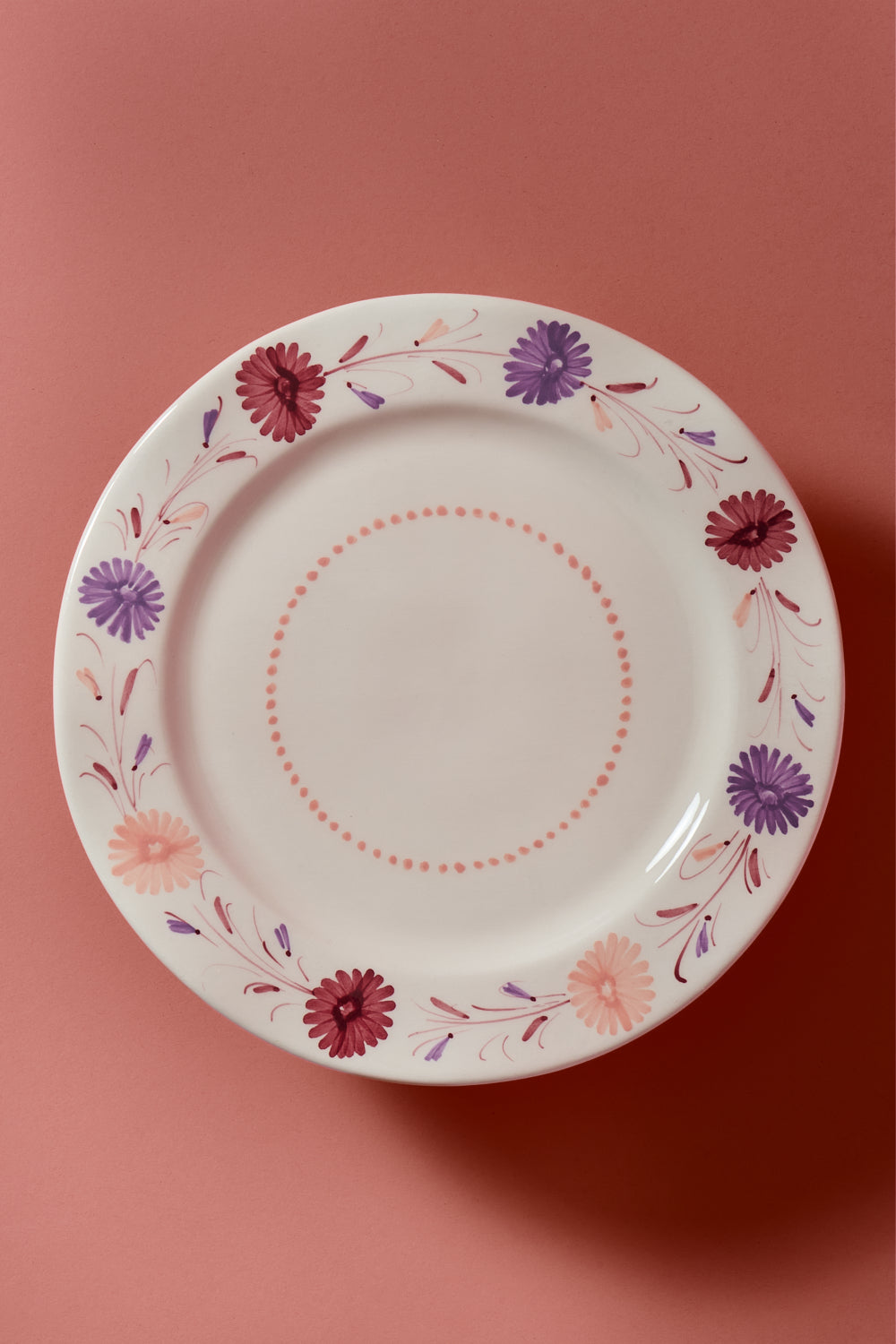 Vaisselle hand painted cake stand with mulberry, peach and lavender floral design on a pink background