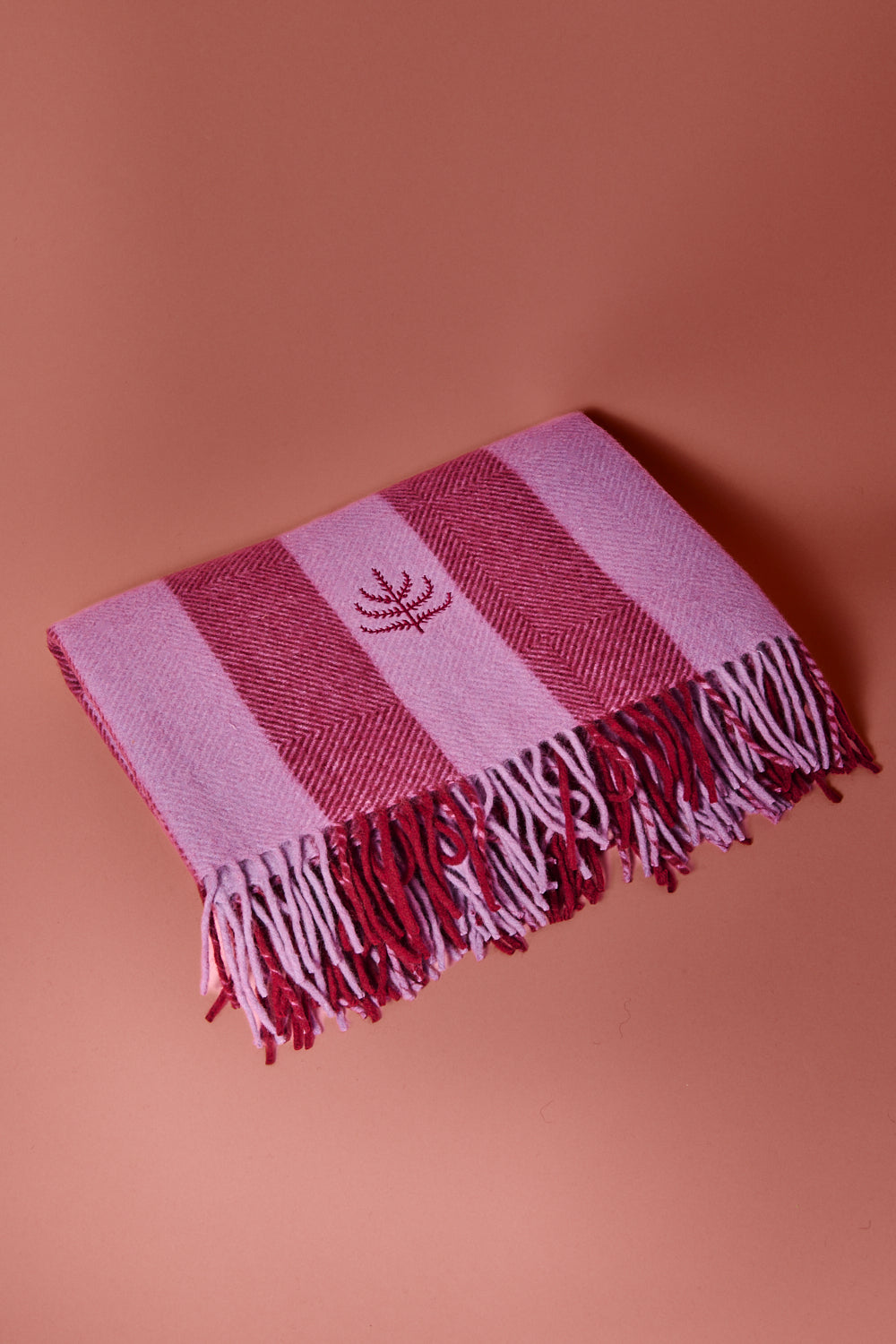Lilac and mulberry striped blanket with the spring and mulberry logo against a brown background