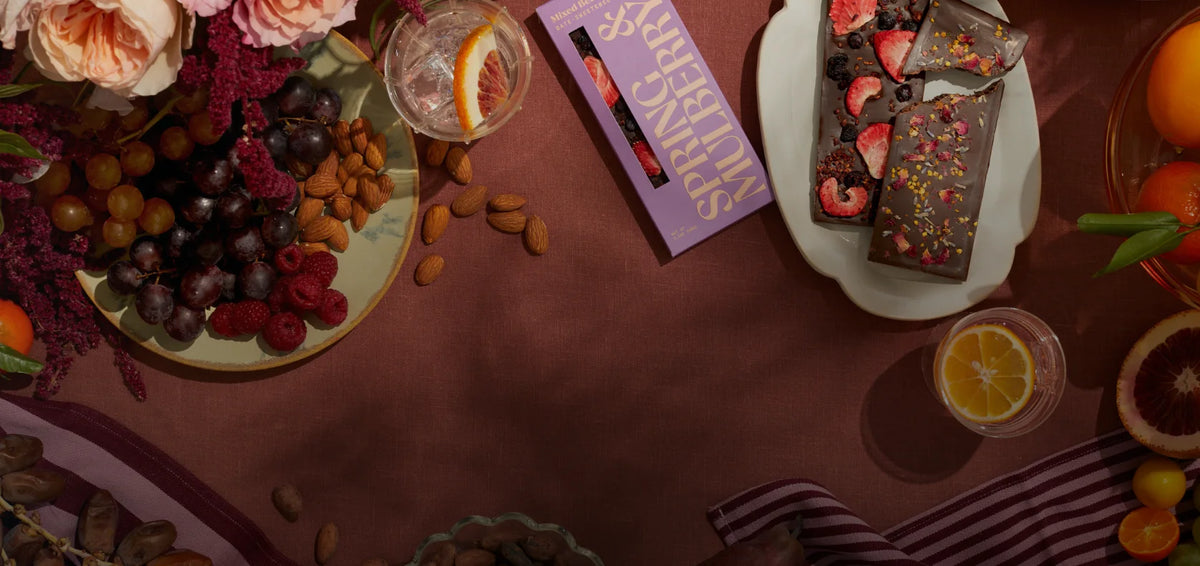 Spring & Mulberry chocolate, fruit, flowers, and drinks arranged on a table
